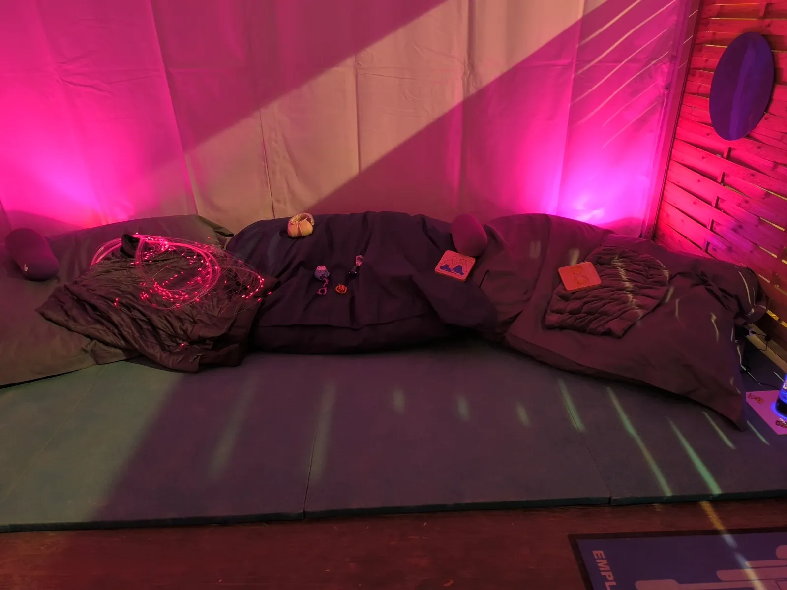 Espace sensoriel de festival aménagé avec poufs, couvertures lestées et fibres lumineuses
