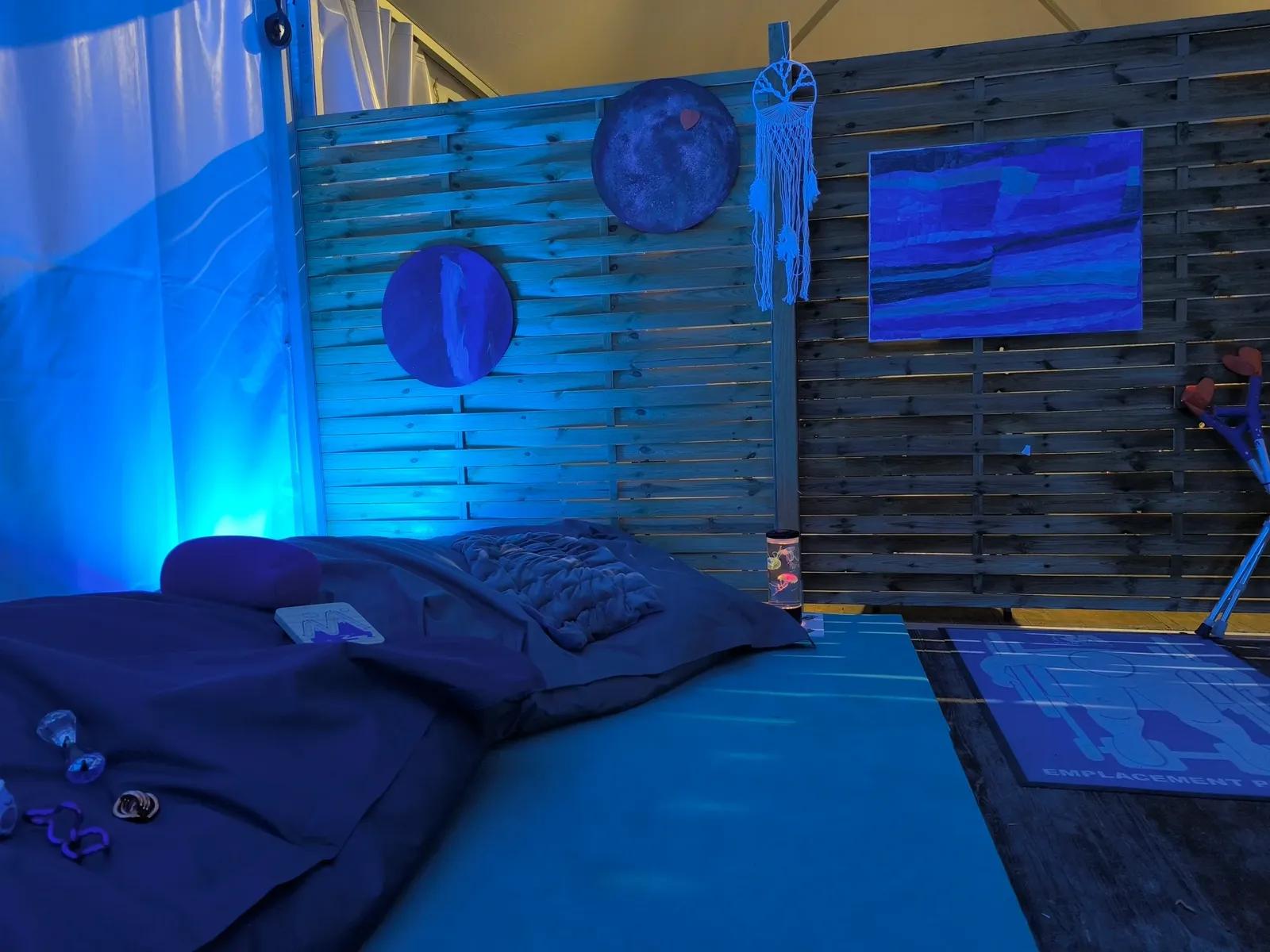 Espace calme de festival avec panneaux en bois, peintures apaisantes et matelas