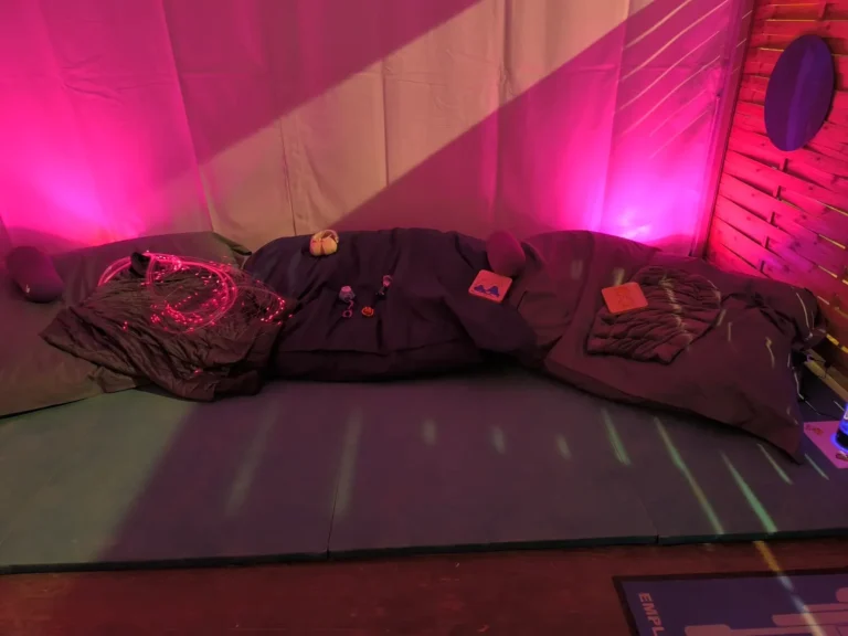 Zone d'autorégulation colorée avec tapis, coussins et lumières tamisées